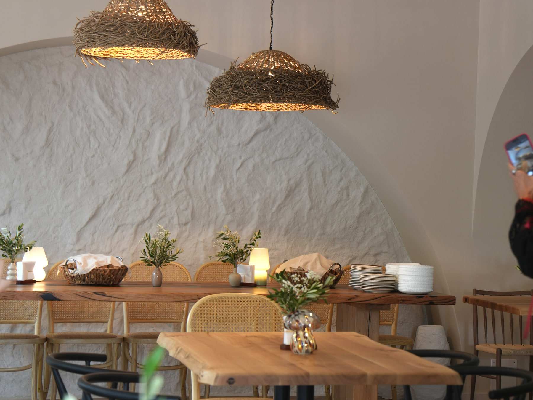 Sala restaurantului HRANA din Hunedoara: arcadă albă texturată, lămpi din nuiele și mese din lemn masiv