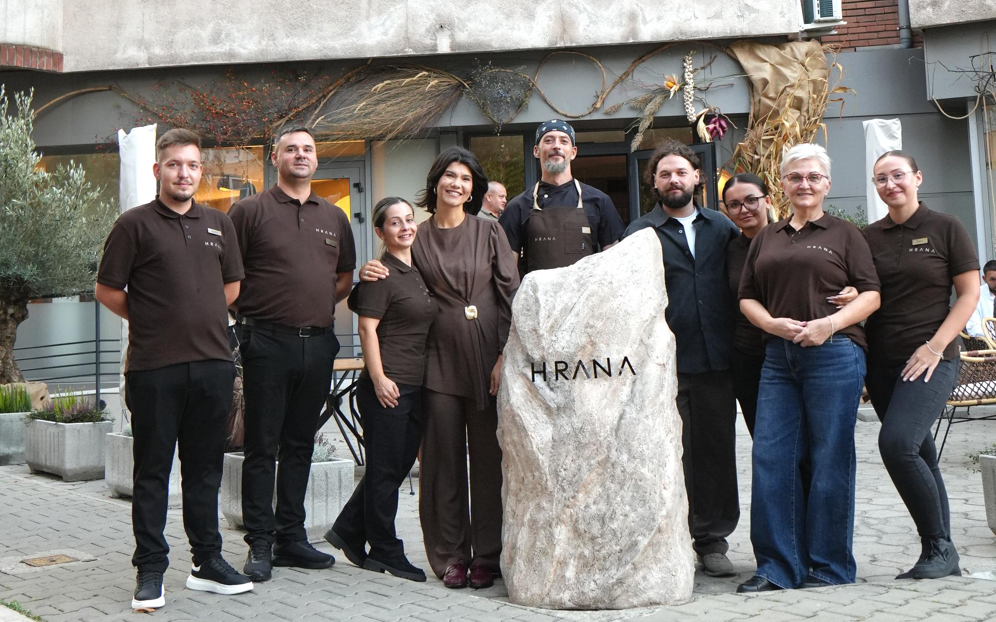 Echipa HRANA în fața pietrei cu logo de la intrarea restaurantului din Hunedoara