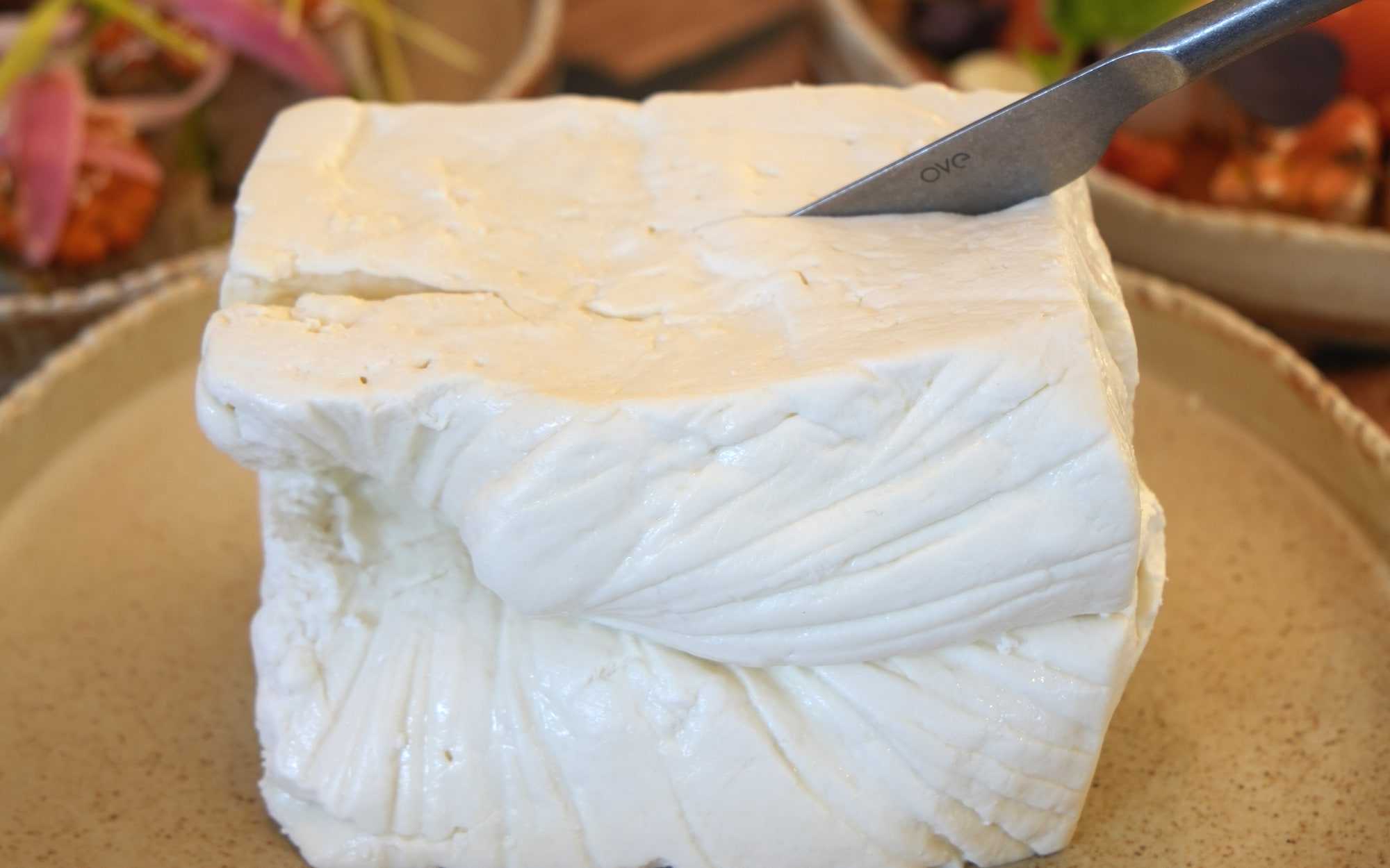 Telemea în tifon pe farfurie de ceramică, lângă boluri cu legume coapte, la HRANA